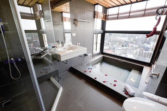 A city apartment features an urban-inspired bathroom with metallic tile walls and matte stone floors. The contrast between these elements offers visual interest to the overall gray space.