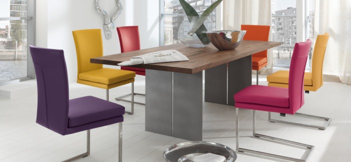 Hard-edged elements like this modern steel dining table can easily be softened and warmed by adding color through brightly multi-hued chairs for a contemporary modern style.