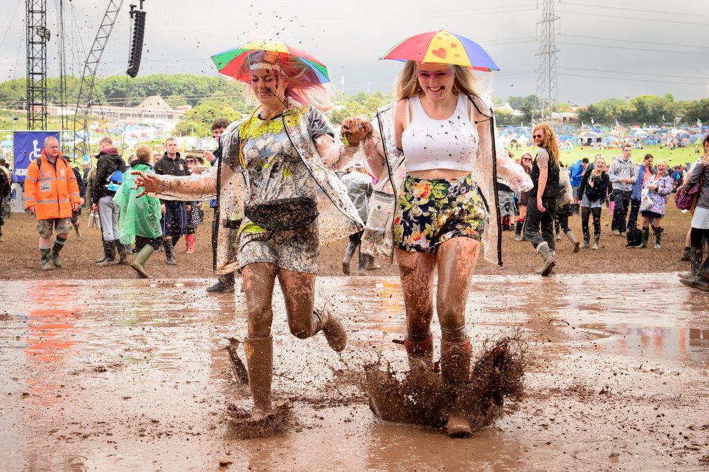 Revellers run through a puddle as they pose for photographers, on the first official day of the Glastonbury Festival of Music and Performing Arts on Worthy Farm in Somerset, south west England, on June 27, 2014. US metal giants Metallica will play this year's coveted Saturday night headline spot at Britain's Glastonbury festival, organisers announced Thursday. It will be the "Master of Puppets" four-piece's first appearance at the legendary festival, held in south west England, following on from The Rolling Stones' Worthy Farm debut last year. AFP PHOTO / LEON NEAL Click here to display all information about this document. (Photo credit should read LEON NEAL/AFP/Getty Images)