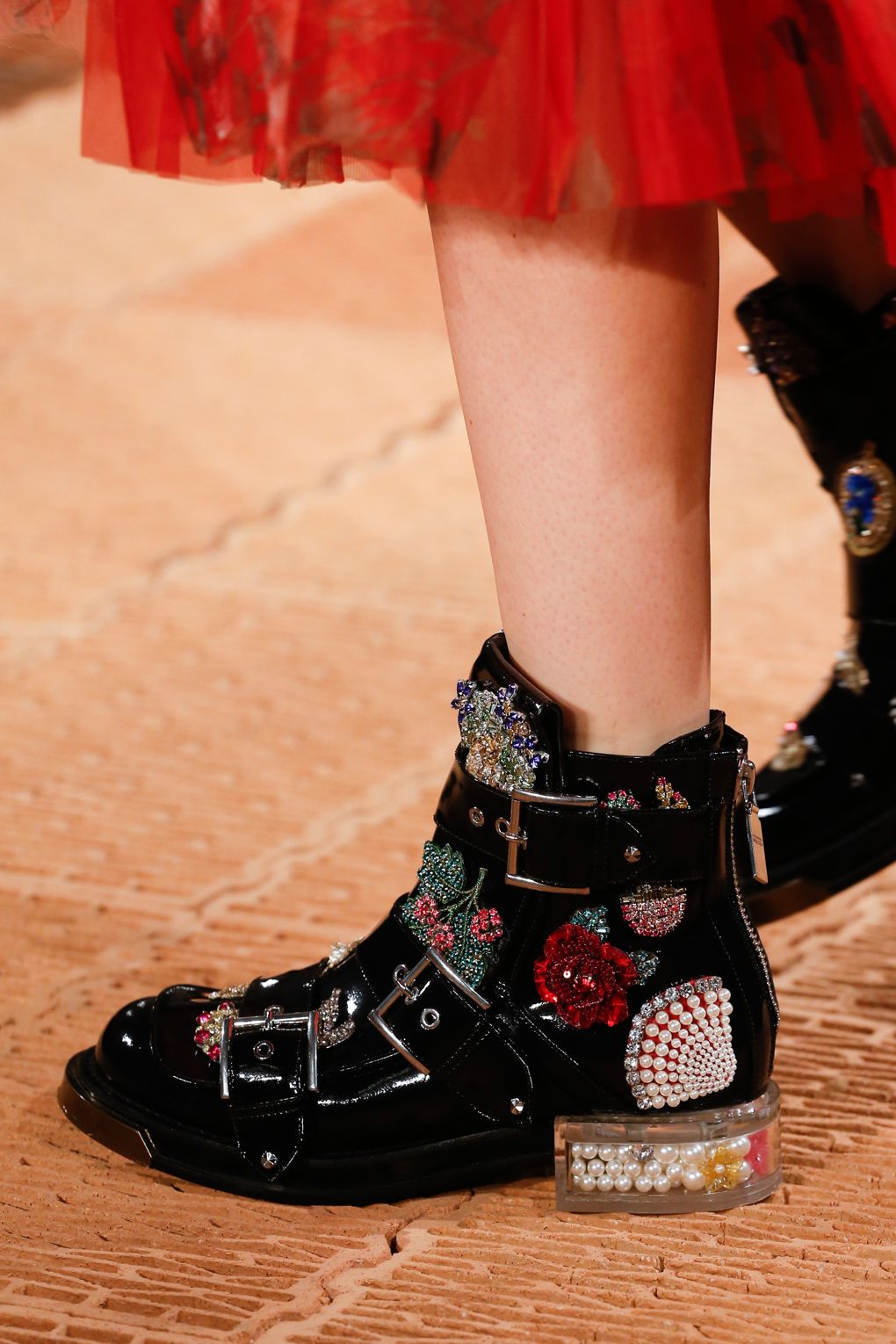 Giám đốc sáng tạo Sarah Burton của Alexander McQueen đã thổi hơi thở nữ tính và trẻ trung vào thiết kế combat boots truyền thống bằng những hình thêu hoa và đính đá thú vị.