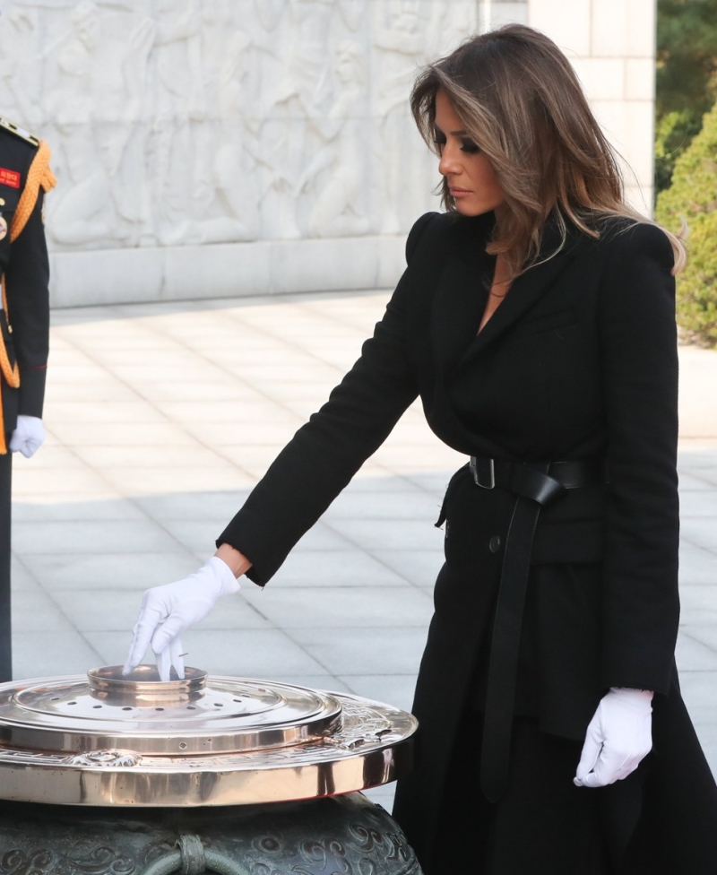 Thăm viếng Nghĩa trang Quốc gia Seoul, Melania Trump mặc chiếc áo khoác màu đen của nhà mốt Alexander McQueen. Điểm nhấn của trang phục là chiếc thắt lưng được cài nút thắt gọn gàng. 