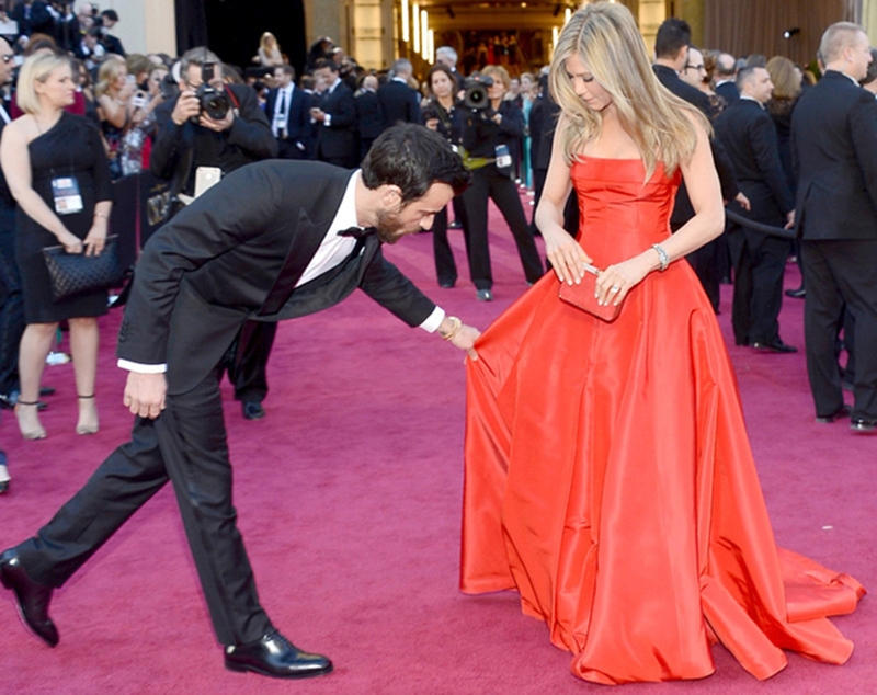 Justin Theroux chỉnh váy cho hôn thê trên thảm đỏ giải Oscar vào tháng 2/2013.