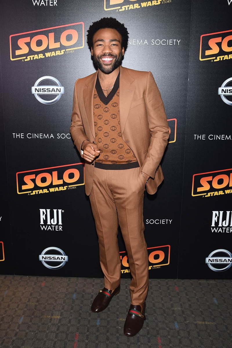 Donald Glover chọn mặc một bộ suit màu nâu sáng của Gucci phối cùng áo len cổ tim đồng điệu.