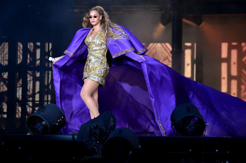 Thiết kế đầm mini với áo choàng tím oversized này là của NTK Peter Dundas với thương hiệu Dundas của riêng mình. Kể từ khi anh cho ra mắt thương hiệu Dundas, Beyoncé chính là một trong những khách VIP có công lăng-xê các sáng tạo của anh tại rất nhiều sự kiện lớn.