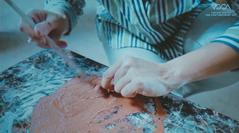 Nghệ sĩ Trần Thu Vân quét gốm trộn keo lên lá.